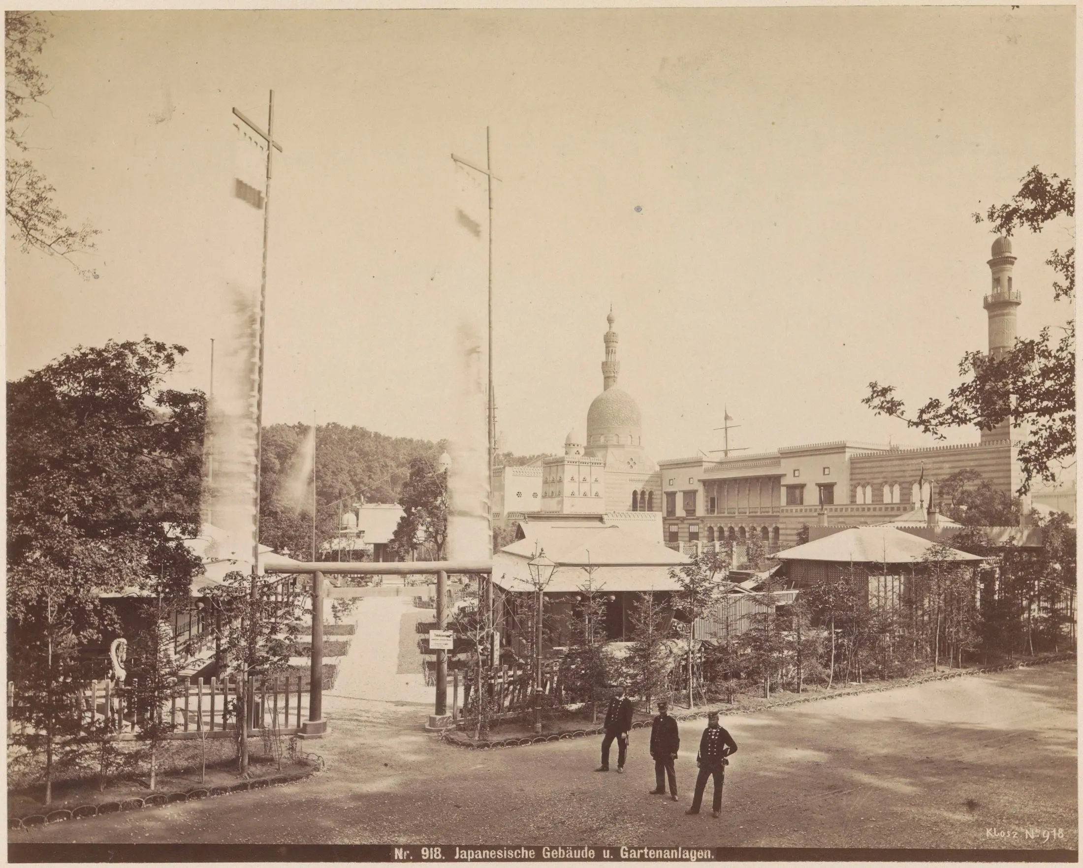 A torii gate, low Japanese pavilion roofs, and a planted garden stand before the domes and minaret of a neighbouring exhibition building in Vienna.